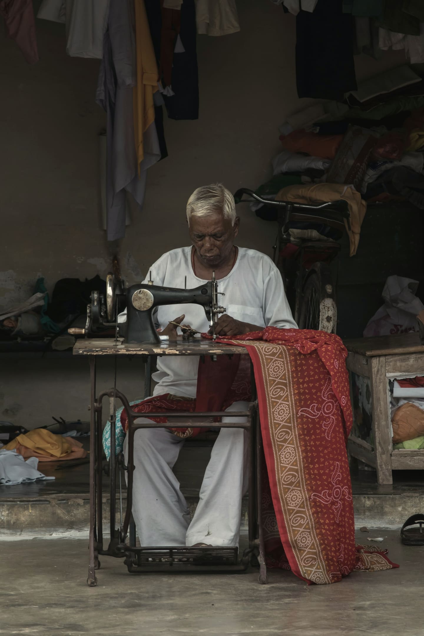 A tailor working at his sewing machine in his shop